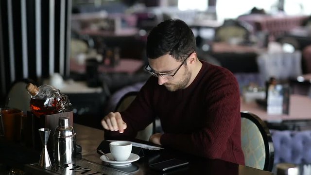 A young man uses tablet while sitting at the bar