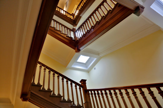 Brown wood staircase with a handrail in a building without an elevator
