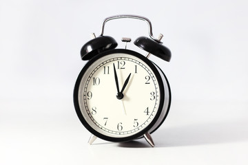 Black alarm clock. Retro clock on the white table. Cream dial