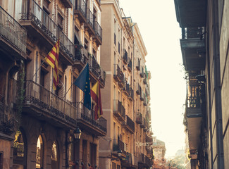 alley at barcelona with some spain and europe flags on building in warm sunlight