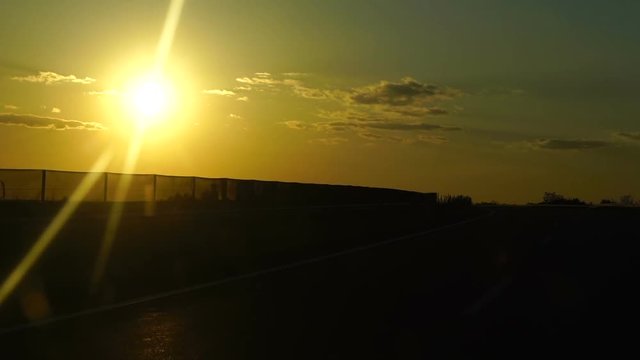 Slow motion: Evening sun through a car of window. Highway at sunset