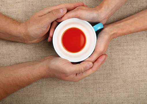 Man and woman hands hold empty black tea cup
