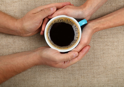 Man and woman hands hold full black coffee cup