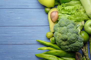 Green vegetables and fruits on wooden background