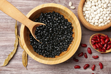 Assortment of haricot beans in bowls on wooden background
