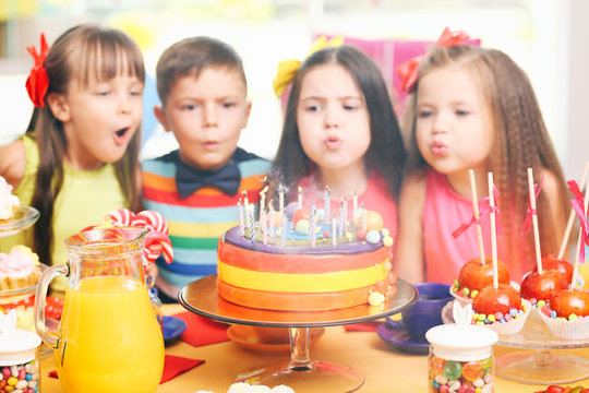 Children blowing candles on tasty cake at birthday party