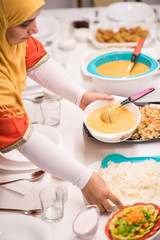 Family gathering eating meal around kitchen table