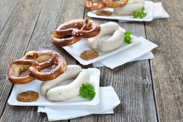 Streetfood bayerisch: Zwei frische Weißwürste mit süßem Senf und Breze auf Pappteller serviert...