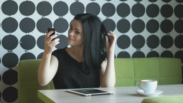 Brunette girl making selfie photo using a mobile phone during coffee break
