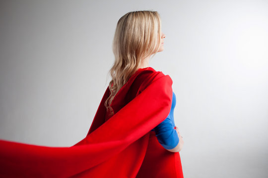 Superhero Woman looking off into the distance at right. Young and beautiful blonde in image of superheroine, back