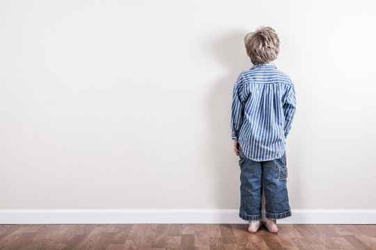 Boy standing up against a wall