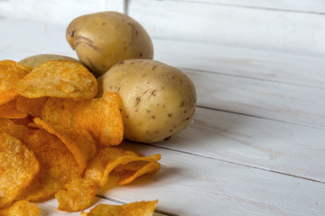 Fresh raw potatoes and chips with spice on a white wooden background