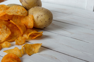 Fresh raw potatoes and chips with spice on a white wooden background