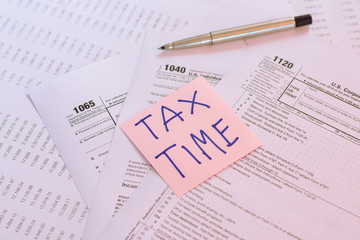 Tax Time written on pink sticker note with on U.S. tax form