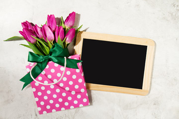 Fresh beautiful lila tulips in gift package on marble background