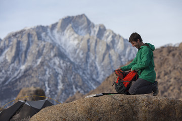 A man taking time for a journal break while camping in the Alabama Hills near the Sierra Nevada Mountains and Lone Pine, California.