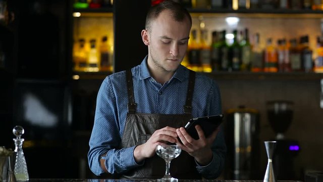 Young bartender exploring new cocktails using tablet