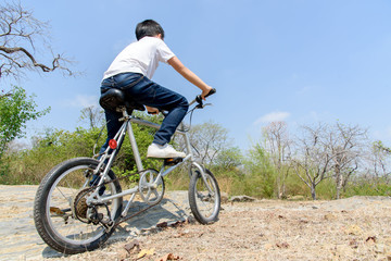 Obraz na płótnie Canvas Little boy ride bicycle on the rock road.