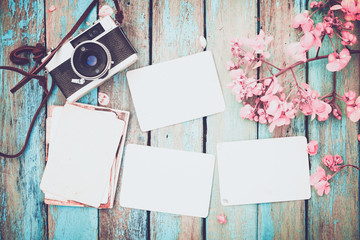 Retro camera and empty old instant paper photo album on wood table with flowers border design -...