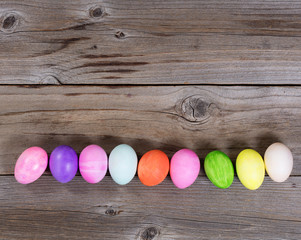 Colorful eggs for Easter holiday forming lower border on wood 