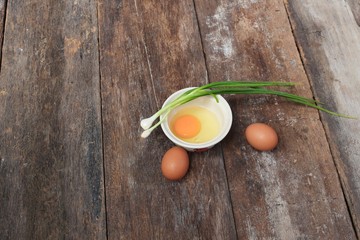 Raw egg in a bowl selective focus and onion on wooden table
