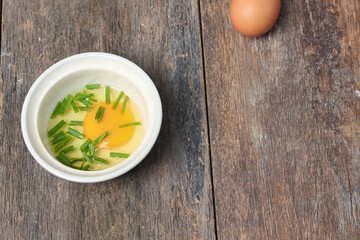 Raw egg in a bowl selective focus and onion on wooden table