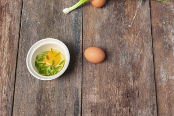 Raw egg in a bowl selective focus and onion on wooden table