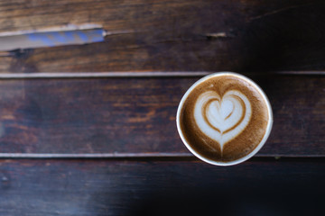hot latte art in paper cup on wood bar view from top.