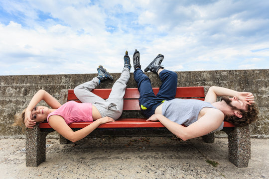 Young tired people friends relaxing on bench.