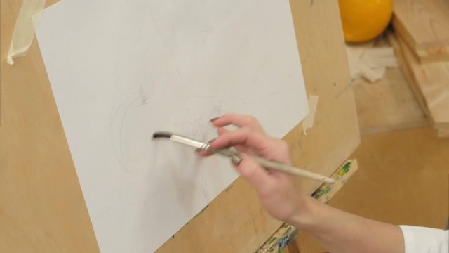 Female painter watering white paper on easel