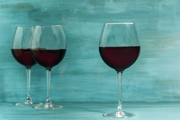 Glasses of red wine on turquoise blue with copyspace