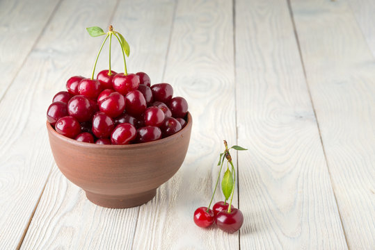 ripe cherries in a bowl on a wooden background