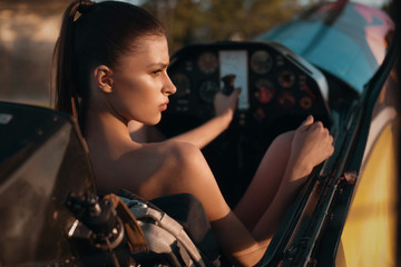Fototapeta na wymiar fashion pilot girl in a cabin of propeller plane on the sunset