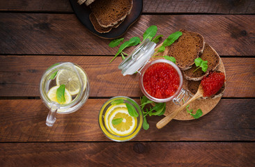 Jar with red caviar and bread on wooden background. Flat lay. Top view