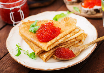 Pancakes with red caviar on plate. Russian cuisine. Maslenitsa