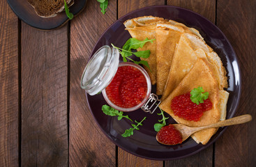 Pancakes with red caviar on plate. Russian cuisine. Maslenitsa. Flat lay. Top view