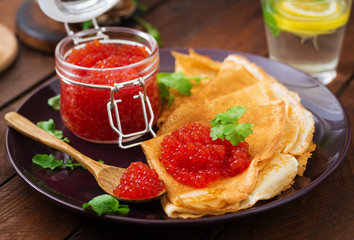 Pancakes with red caviar on plate. Russian cuisine. Maslenitsa