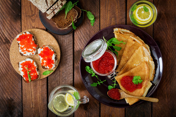 Pancakes with red caviar on plate. Russian cuisine. Maslenitsa. Flat lay. Top view