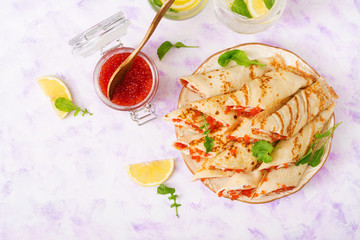 Pancakes with red caviar on plate. Russian cuisine. Maslenitsa. Flat lay. Top view