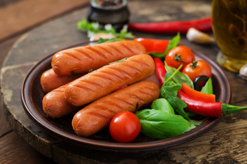 Grilled sausages and vegetables on a wooden background in rustic style.