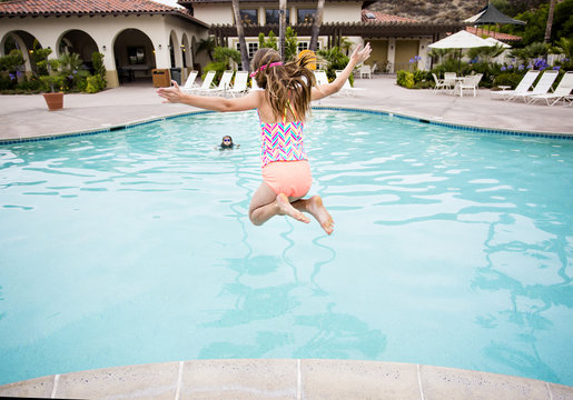 Child jumping into a big swimming pool 
