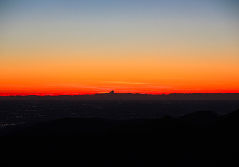 Fiery sunset from mountain pick with thin glazes in the sky evening. Fall season. Orobie alps. Rena pick. Bergamo Italy. In the distance the Monviso.