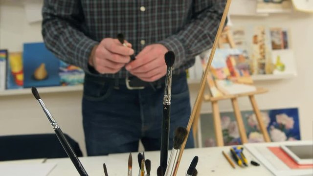 Male painter choosing different brushes for work