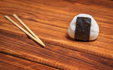 Japanese onigiri with chopsticks on wooden background. Rice ball