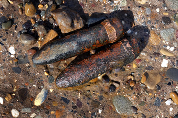 Spent twenty millimeter canon shells in sand on a UK east coast beach near world war two practice firing ranges.