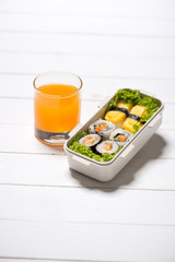 Orange juice and bento box with different food, fresh veggies an