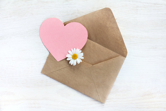 greeting happy lovers/ heart symbol with chamomile peeks out the open envelope, top view