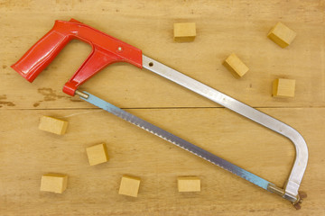 cutting wood with hand saw on wooden background