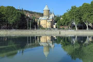 Fototapeta na wymiar Tbilisi Sioni Cathedral reflected in the water of Kura River in summer morning, Georgia