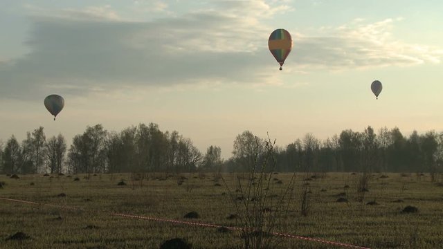 Three balloons hovering over a field